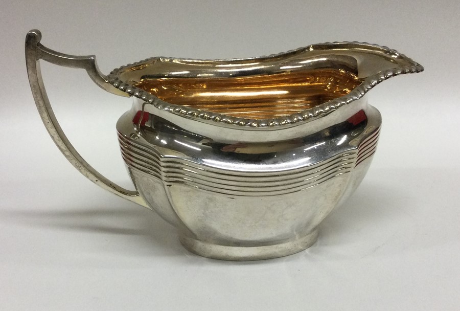A heavy silver shaped cream jug with gadroon rim.