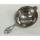 A stylish silver tea strainer with pierced handle.