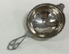 A stylish silver tea strainer with pierced handle.