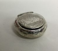 A circular hinged top silver box with scroll decor