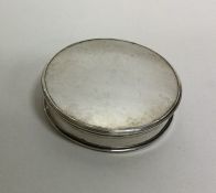 A circular silver pill box with reeded decoration.