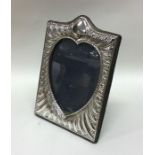 A scroll decorated heart shaped silver picture fra