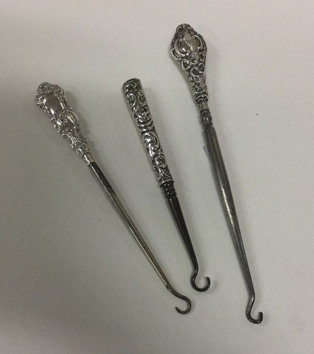 A group of three silver handled button hooks. Appr