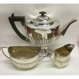 A large silver three piece half fluted tea service