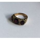 A large gold and garnet nine stone ring in claw mo