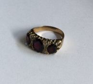 A large gold and garnet nine stone ring in claw mo