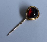 A large cabochon garnet stick pin with ball decora