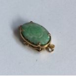 A jade and gold oval carved clasp in claw mount. A