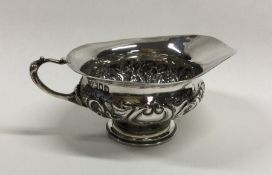 A Victorian chased silver squat cream jug. London