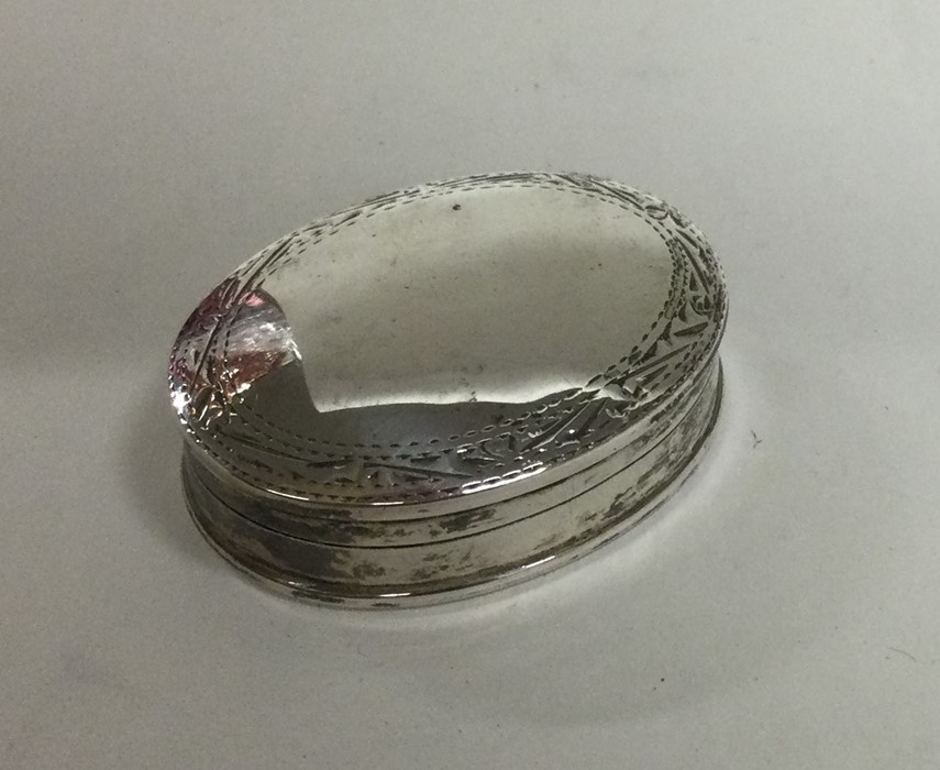 An Edwardian silver pill box with engraved decorat