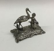 A cast silver table toy in the form of a cherub on