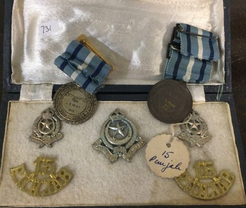 A box containing cap badges etc. Est. £10 - £20.