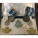 A box containing cap badges etc. Est. £10 - £20.