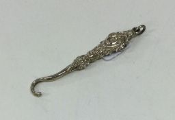 A miniature silver embossed button hook with loop