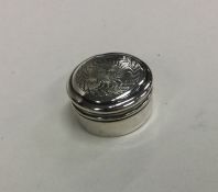 A small silver pill box decorated with flowers and