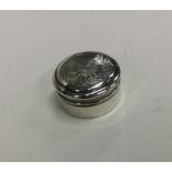 A small silver pill box decorated with flowers and