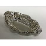 An oval silver pierced bonbon dish with scroll dec