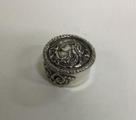 A small circular silver pill box decorated with a