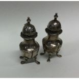 A pair of Edwardian silver peppers on four cabriol