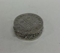 A heavy circular silver pill box decorated with fl