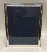 A large silver picture frame with beaded rim. Lond