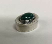 An oval silver pill box with cabochon stone to hin