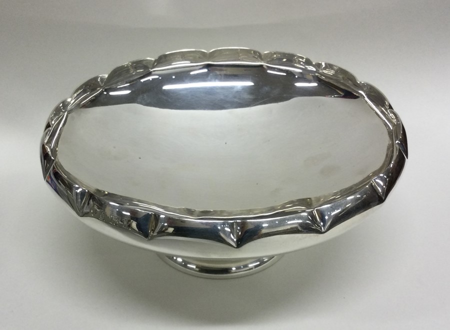 A large circular silver pedestal bowl with crimped