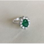 A good emerald and diamond circular cluster ring i