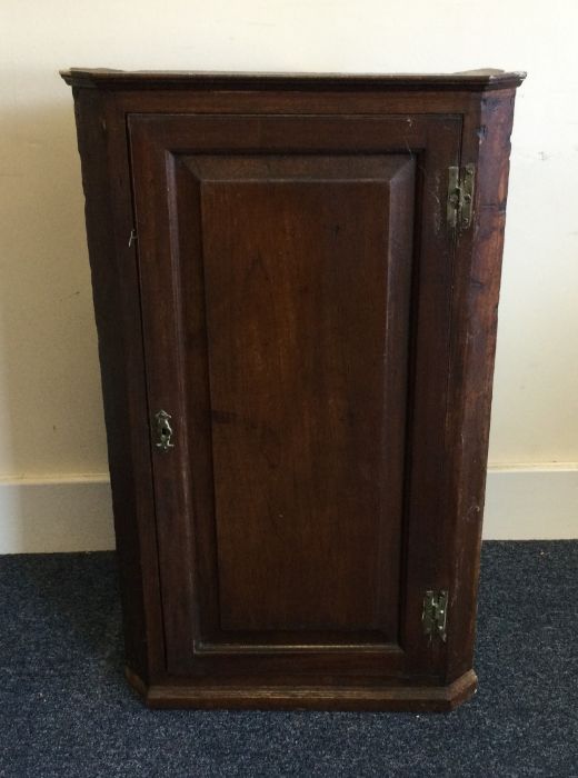 A Georgian oak corner cupboard with brass hinges.