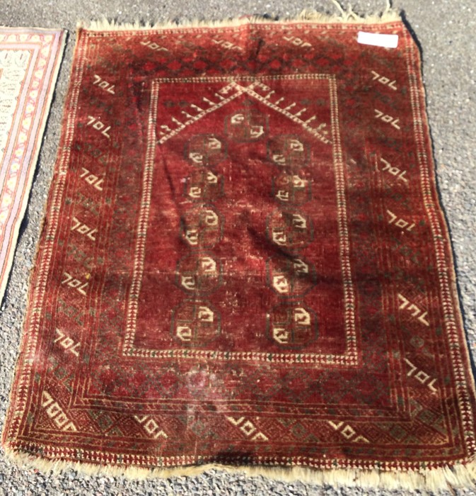 An old red ground rug. Est. £30 - £50.