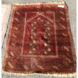 An old red ground rug. Est. £30 - £50.