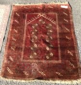 An old red ground rug. Est. £30 - £50.