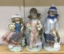 Three Lladro figures of young children on green ba