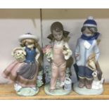 Three Lladro figures of young children on green ba