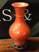 A Chinese red ground baluster shaped vase on woode