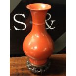 A Chinese red ground baluster shaped vase on woode