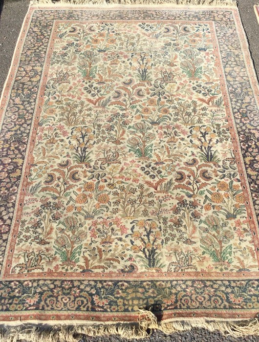 A large Oriental rug in pink ground with tassel ed