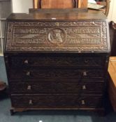 A Georgian style carved oak bureau decorated with