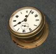 A large brass ship's clock with white enamelled di