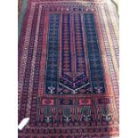 An old red ground rug. Est. £20 - £30.