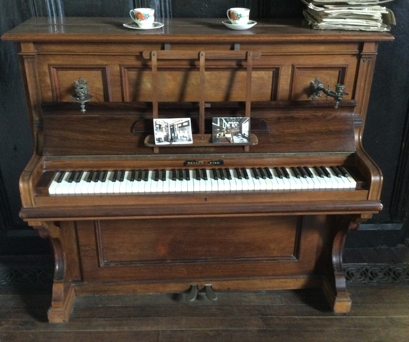 A large mahogany upright piano with brass handles