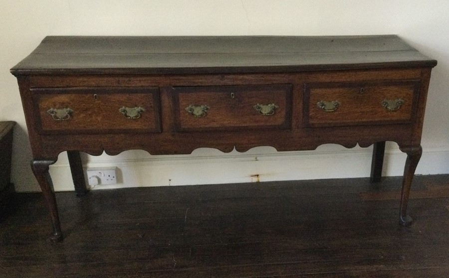 A Georgian oak three drawer dresser base with cros