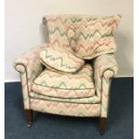 A Victorian upholstered armchair on tapering suppo
