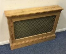 A stripped pine radiator cover with mesh front. Es