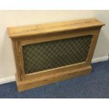A stripped pine radiator cover with mesh front. Es