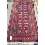 An old red ground rug. Est. £30 - £50.