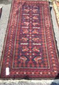 An old red ground rug. Est. £30 - £50.