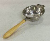 A circular silver tea strainer with reeded body. B