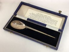 A cased silver preserve spoon with textured body.