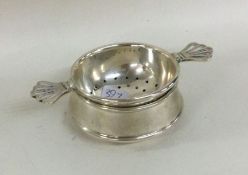 A stylish silver tea strainer on stand with pierce